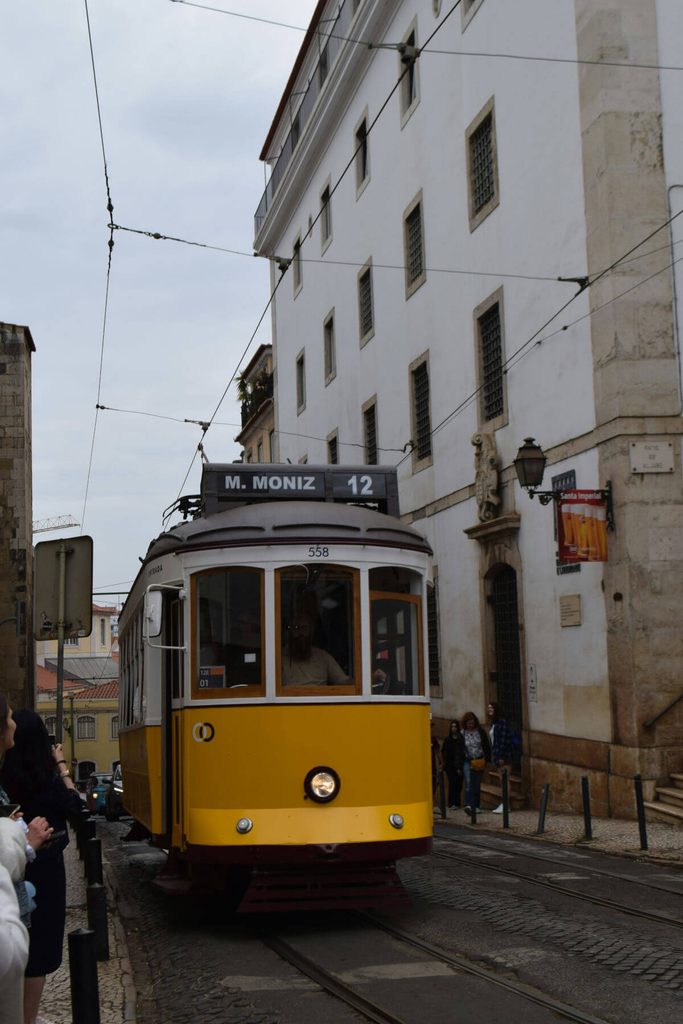 Tramway jaune traditionnel dans une rue pavée du quartier de l'Alfama à Lisbonne