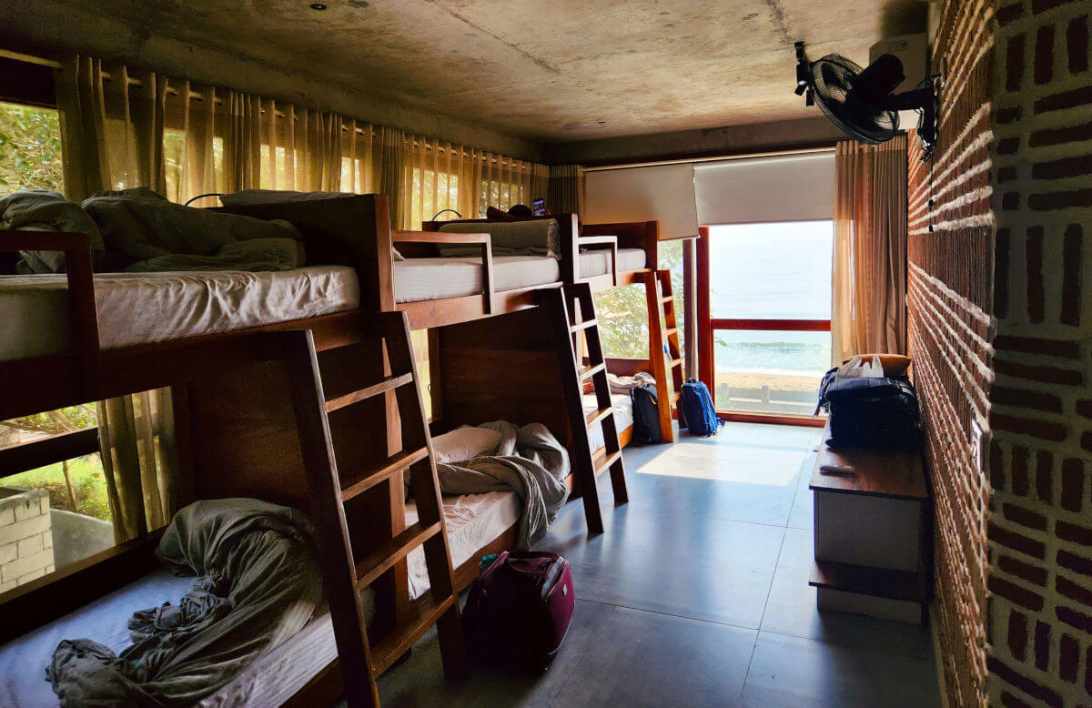 Dortoir d'auberge de jeunesse en bois avec lits superposés et vue sur la mer