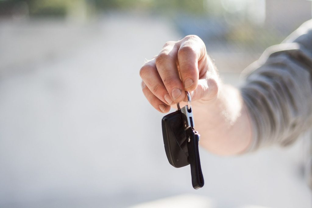 Main tendant une clé de voiture, au moment de récupérer une voiture de location