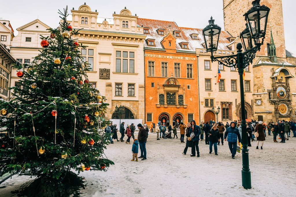 Sapin de Noël enneigé sur la place de la Vieille-Ville à Prague, devant l'horloge astronomique